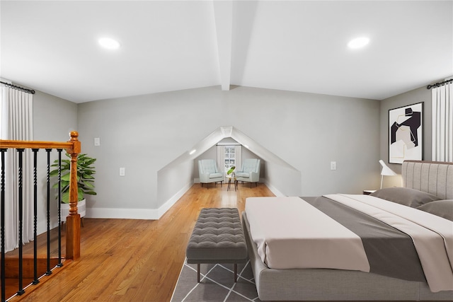 bedroom with lofted ceiling with beams and light hardwood / wood-style floors