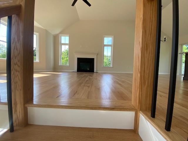 unfurnished living room featuring ceiling fan, a healthy amount of sunlight, and lofted ceiling