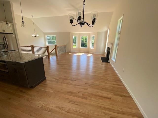 interior space featuring lofted ceiling, light wood-type flooring, and a notable chandelier