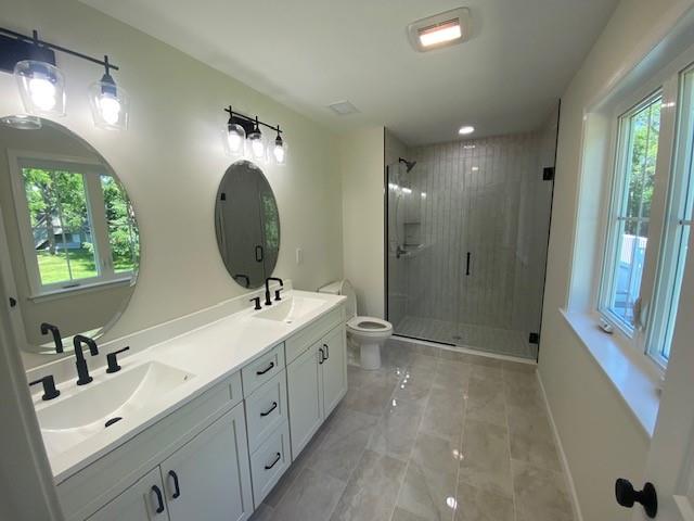 bathroom with walk in shower, vanity, and toilet