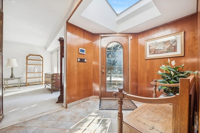 foyer entrance featuring light carpet, wood walls, and a skylight