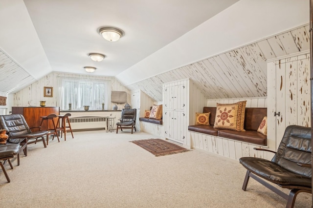 living area with radiator, lofted ceiling, carpet flooring, and wood walls