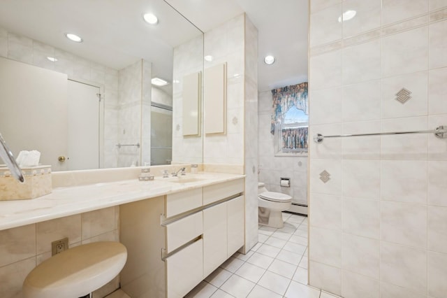 bathroom with tile patterned floors, a baseboard heating unit, toilet, tile walls, and vanity