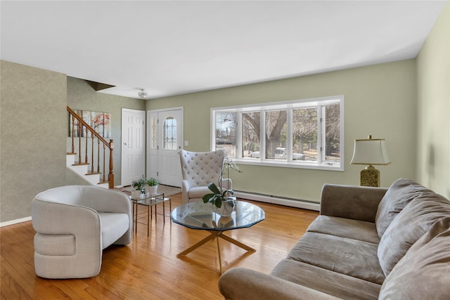 living area featuring a baseboard radiator, baseboards, wood finished floors, and stairway