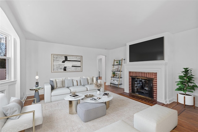 living room featuring a brick fireplace and wood-type flooring