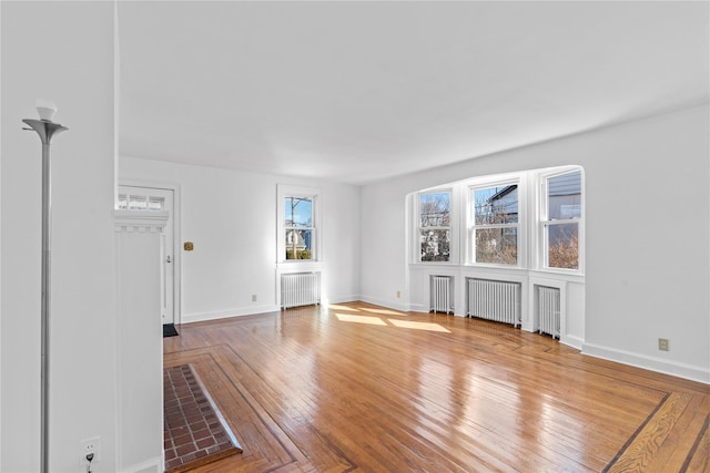 unfurnished living room featuring hardwood / wood-style flooring and radiator heating unit