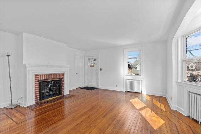 unfurnished living room with radiator, hardwood / wood-style flooring, and a fireplace