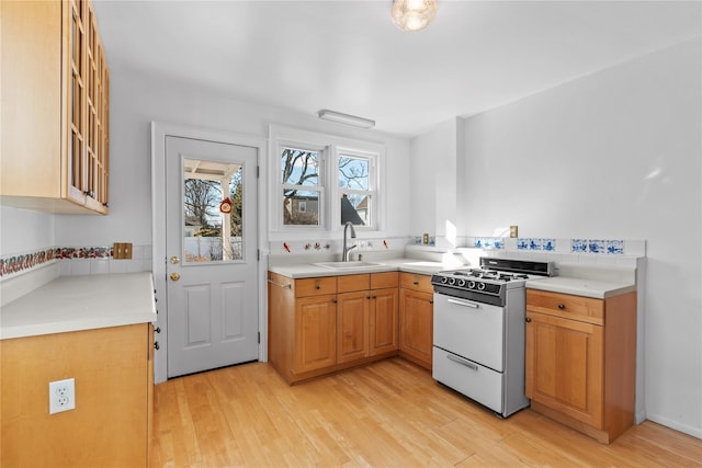 kitchen with sink, white gas range oven, and light wood-type flooring