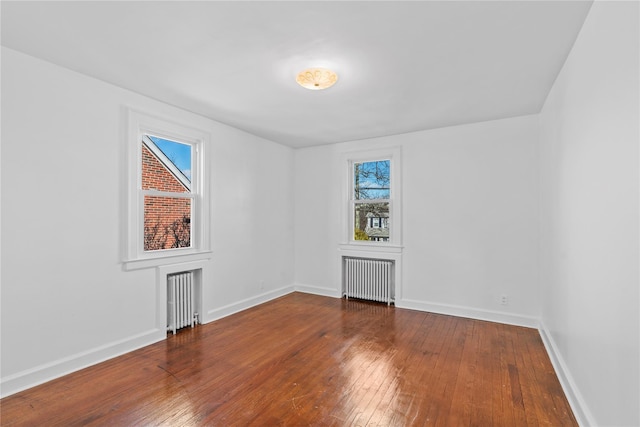 empty room featuring hardwood / wood-style floors and radiator heating unit