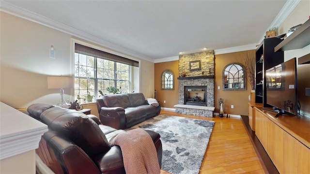 living area with light wood-type flooring, baseboards, ornamental molding, and a stone fireplace