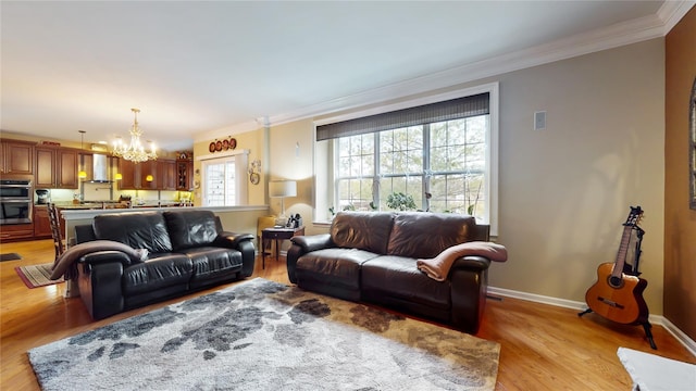 living room featuring baseboards, crown molding, light wood finished floors, and an inviting chandelier