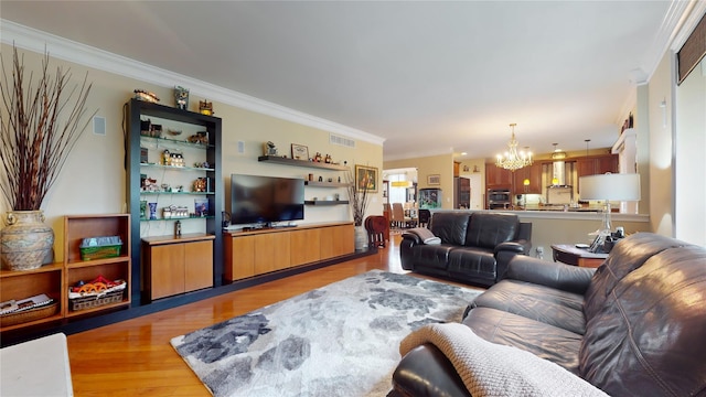 living area with a chandelier, crown molding, visible vents, and light wood-style floors