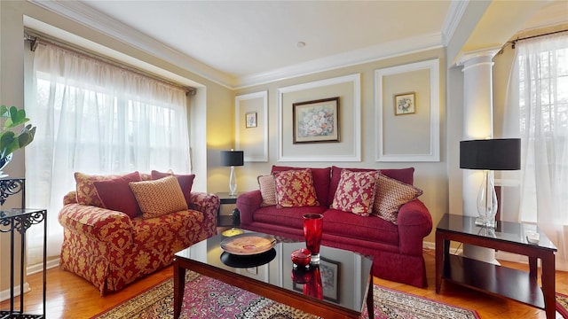 living area featuring a healthy amount of sunlight, crown molding, ornate columns, and wood finished floors