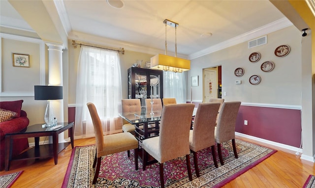 dining room featuring ornate columns, wood finished floors, visible vents, and crown molding