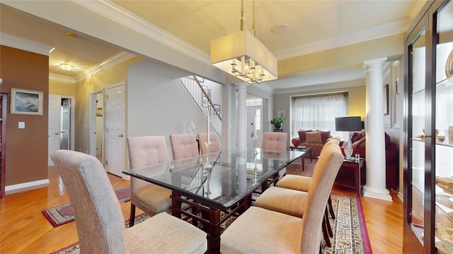 dining space with light wood-type flooring, ornate columns, stairs, and ornamental molding