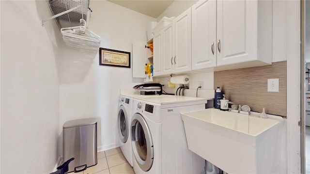 clothes washing area with independent washer and dryer, cabinet space, a sink, and light tile patterned floors