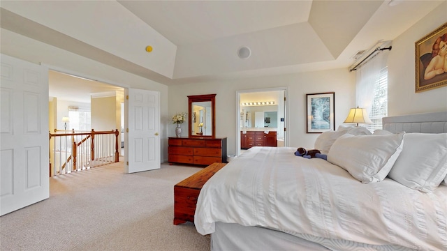 bedroom featuring lofted ceiling, a raised ceiling, light colored carpet, and ensuite bathroom