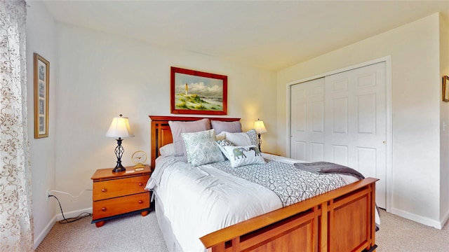 bedroom featuring baseboards, a closet, and light colored carpet