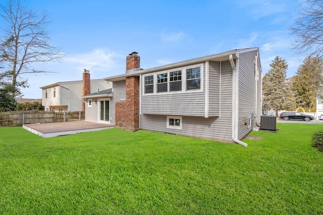 back of house featuring central air condition unit, a chimney, fence, and a lawn