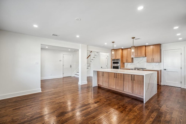 kitchen featuring visible vents, dark wood finished floors, a large island, light countertops, and stainless steel double oven