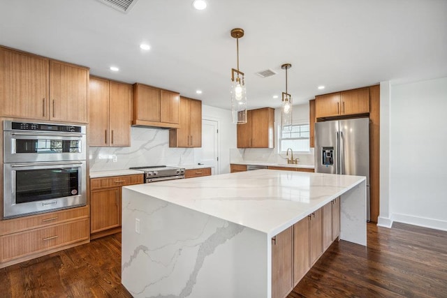 kitchen featuring dark wood-style floors, a center island, visible vents, appliances with stainless steel finishes, and a sink