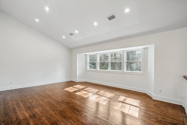 empty room featuring wood-type flooring, visible vents, and baseboards