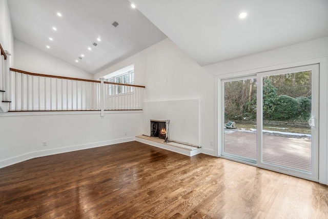 unfurnished living room with recessed lighting, wood finished floors, high vaulted ceiling, a warm lit fireplace, and baseboards