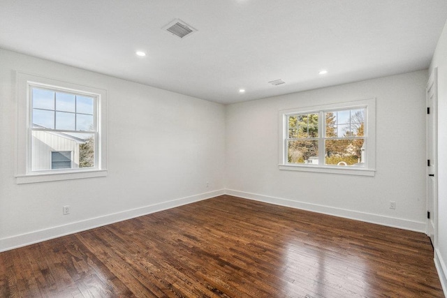 empty room featuring baseboards, visible vents, dark wood-style flooring, and recessed lighting