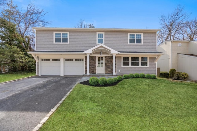 view of front of property featuring driveway, stone siding, an attached garage, and a front lawn