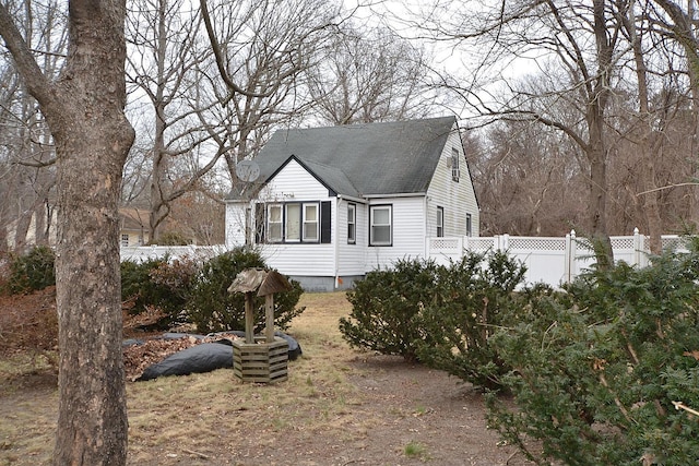 view of side of home featuring a shingled roof and fence