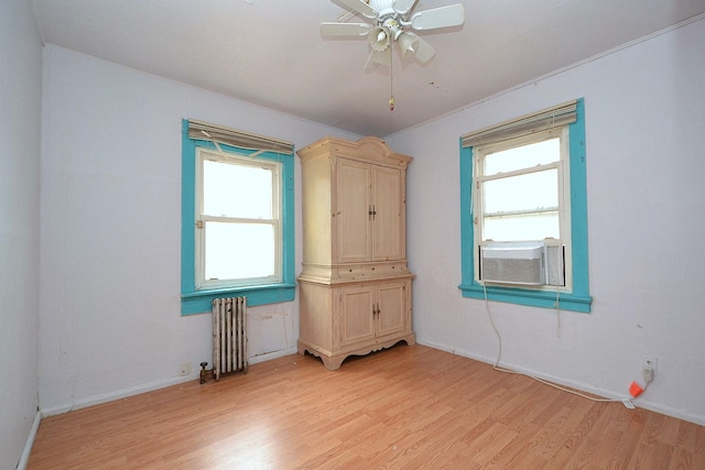 spare room featuring baseboards, light wood-style floors, a wealth of natural light, and radiator