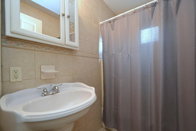 full bathroom with a sink, tile walls, and a shower with shower curtain