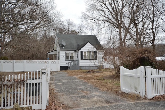 view of front facade featuring roof with shingles, fence private yard, and a gate