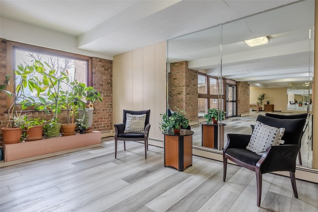 living area with brick wall and light wood-style flooring