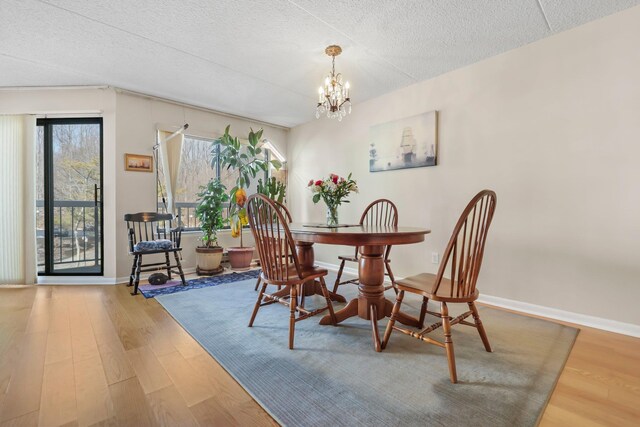 dining room featuring baseboards, a textured ceiling, an inviting chandelier, and wood finished floors