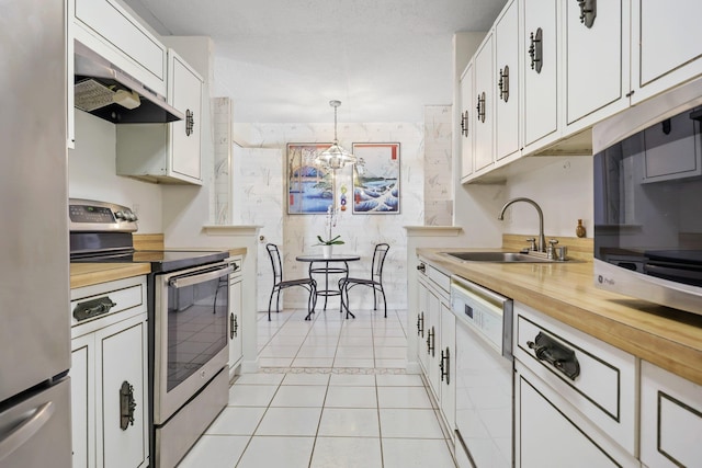 kitchen with hanging light fixtures, appliances with stainless steel finishes, a sink, and white cabinets