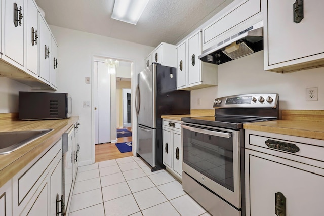 kitchen featuring light tile patterned floors, white cabinets, appliances with stainless steel finishes, under cabinet range hood, and a sink