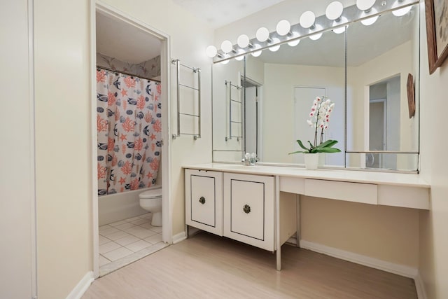 bathroom featuring toilet, shower / tub combo, wood finished floors, vanity, and baseboards