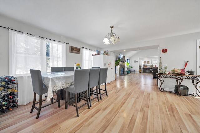 dining area featuring light hardwood / wood-style flooring, vaulted ceiling, and a notable chandelier