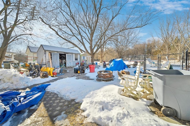 yard covered in snow with a shed and an outdoor fire pit