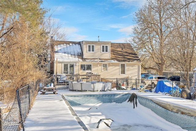 snow covered rear of property featuring a swimming pool side deck