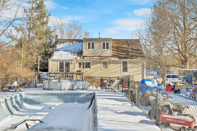 snow covered rear of property with a swimming pool