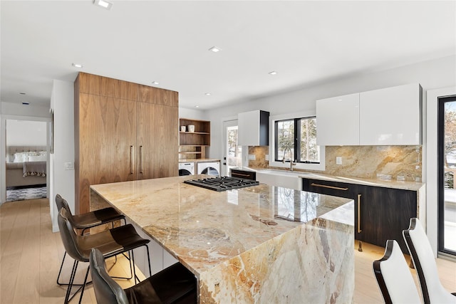 kitchen featuring white cabinetry, a large island, light stone counters, and a kitchen bar