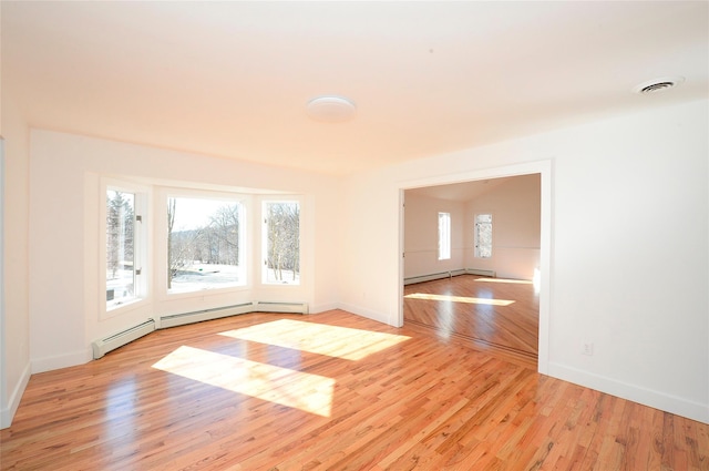 empty room featuring a baseboard heating unit and light wood-type flooring