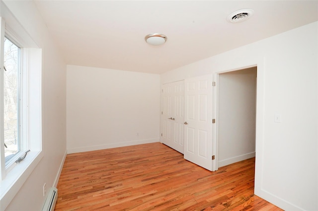 spare room with a baseboard heating unit and light wood-type flooring