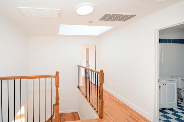 hallway with a skylight and light wood-type flooring