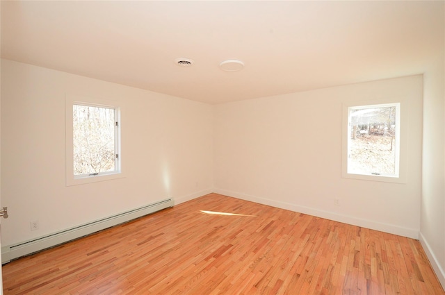 unfurnished room with baseboard heating and light hardwood / wood-style floors