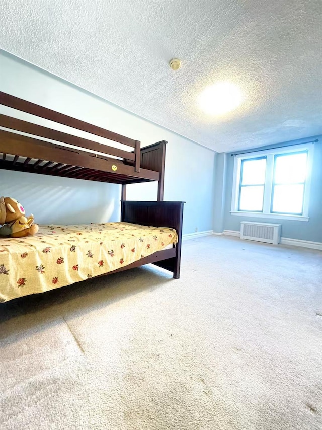 unfurnished bedroom featuring radiator, carpet floors, and a textured ceiling