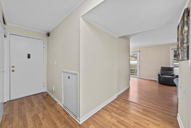 hall featuring light wood-style floors, baseboards, and ornamental molding