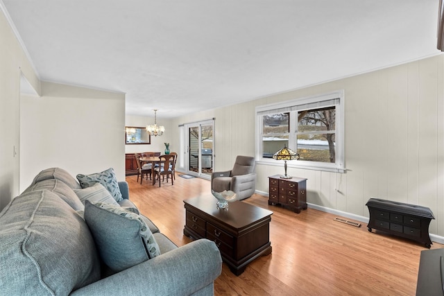 living area featuring baseboards, wood finished floors, visible vents, and an inviting chandelier